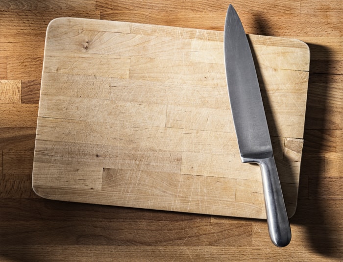 couteau en acier inoxydable sur une planche à découper sur un comptoir en bois