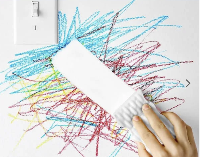 L'éponge magique efface le crayon du mur blanc près de l'interrupteur.