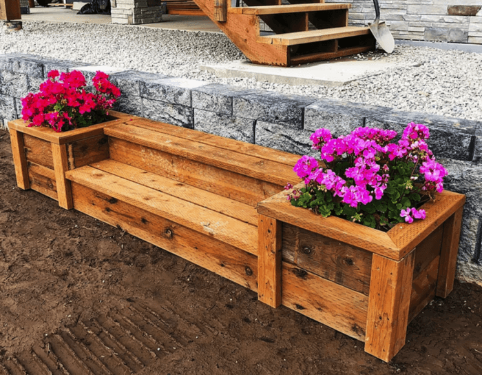 banc en bois dans un jardin paysager flanqué de deux jardinières encastrées avec des fleurs