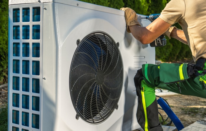 technicien travaillant sur une pompe à chaleur à l'extérieur