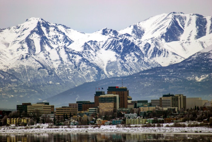 vue d'un lac au premier plan et de la ville d'Anchorage en Alaska avec des montagnes à l'arrière-plan