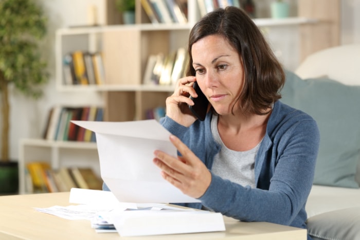 Une femme au téléphone regarde des papiers.