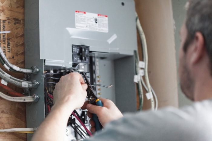 12 façons de rendre une vieille maison plus économe en énergie - un homme travaillant sur un panneau électrique