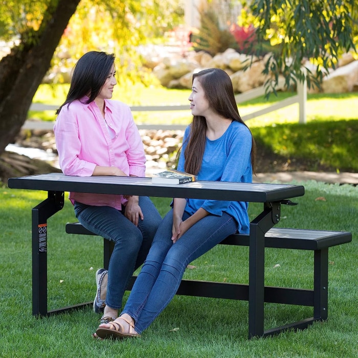 Banc de jardin convertible avec deux femmes discutant et assises dessus.