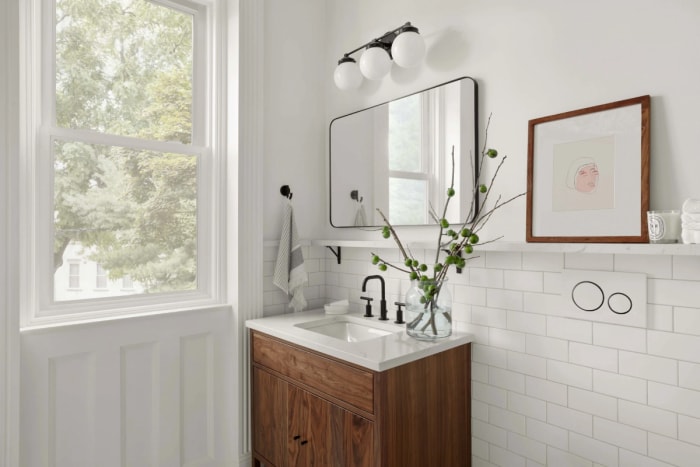 Salle de bain blanche avec plante dans un vase transparent.