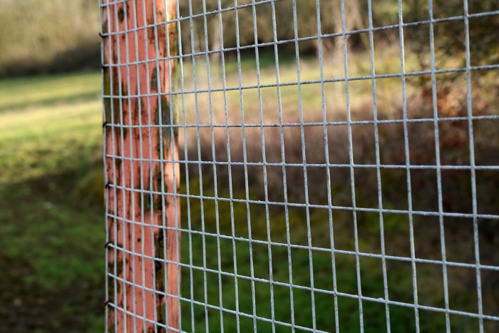 Une clôture en fil de fer est attachée à un poteau en bois sur une propriété rurale.