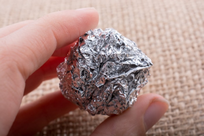 Personne tenant une boule de papier d'aluminium