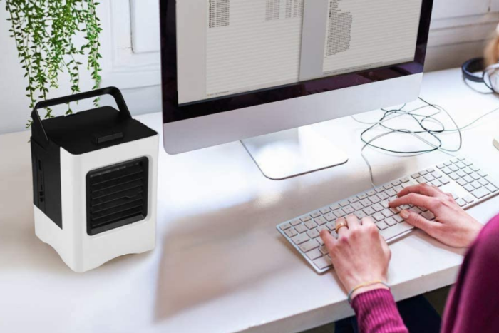 La meilleure option de climatiseur personnel se trouve sur le bureau d'une femme travaillant sur un ordinateur.