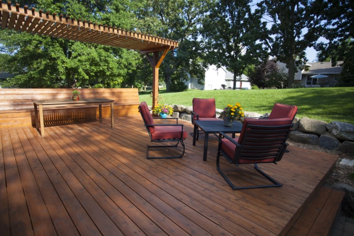 Terrasse avec mobilier de patio rouge et pergola recouvrant une table de pique-nique.