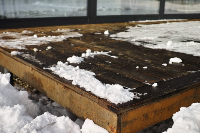 une-terrasse-en-bois-avec-de-la-glace-et-de-la-neige