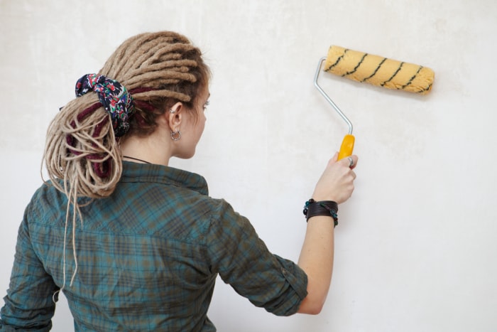 femme appliquant une couche de fond sur un mur à l'aide d'un rouleau