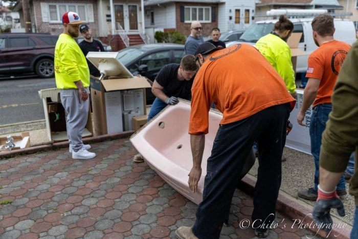 Des bénévoles aident à déplacer une nouvelle baignoire dans une maison à Jersey City.