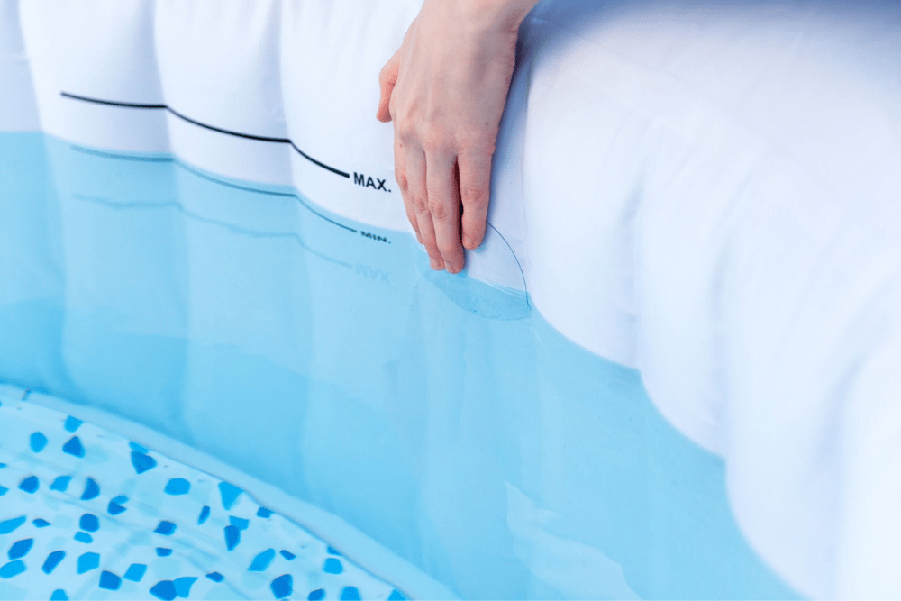 Une main fixant la meilleure option de patch de piscine sur le côté intérieur d'une piscine gonflable remplie d'eau