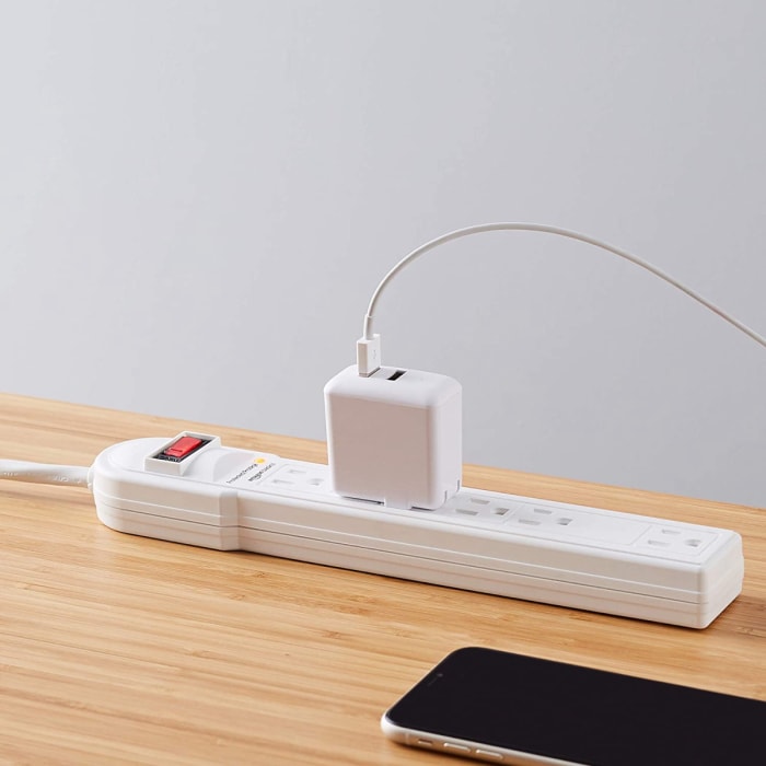 Photo du produit d'un parasurtenseur Amazon Basics avec un chargeur de téléphone branché dessus