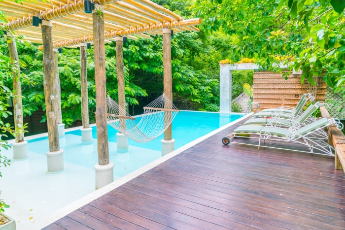 Des chaises longues au bord d'une petite piscine, le tout dans une ambiance tropicale.