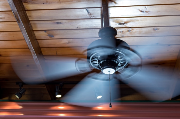 Un ventilateur de plafond présente un flou de mouvement lorsque ses pales tournent.