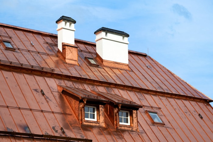 Une maison avec un grand toit en cuivre contre un ciel bleu. 