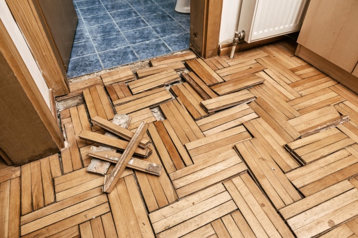 Le parquet d'une salle de bains est déformé et endommagé par l'humidité.