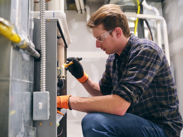 Un réparateur travaillant à l'intérieur d'une maison, réparant une fournaise.