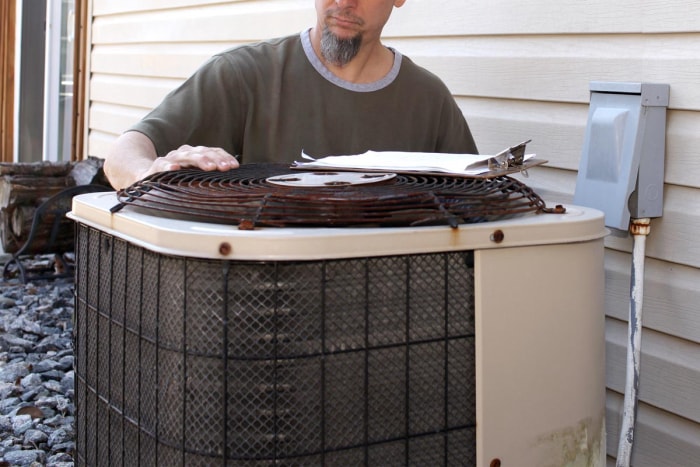 Un ouvrier inspecte le circuit d'un ancien modèle de climatiseur.