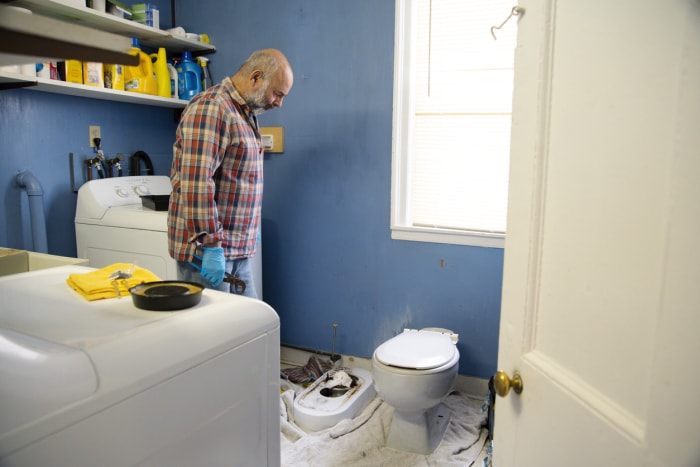 Un homme répare la salle de bain et la buanderie d'une vieille maison