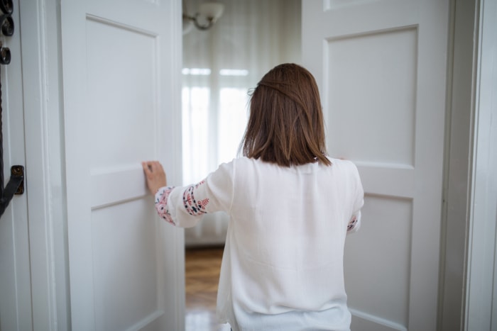 Vue de dos d'une femme ouvrant les portes d'une grande pièce.