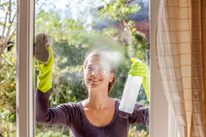 Femme nettoyant une fenêtre de l'extérieur