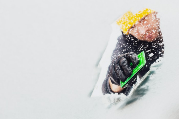 Des choses que vous pouvez utiliser lorsque vous n'avez pas de grattoir à glace - homme grattant la neige sur le pare-brise