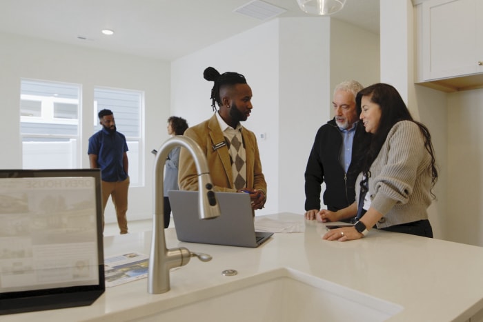 Agent immobilier aidant un couple lors d'une journée portes ouvertes.