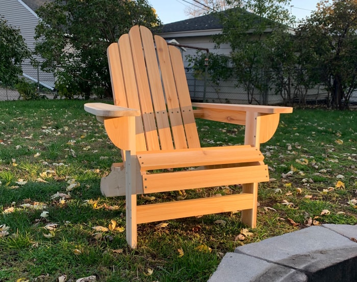 Une chaise Adirondack à faire soi-même dans une cour arrière de banlieue près d'un foyer.