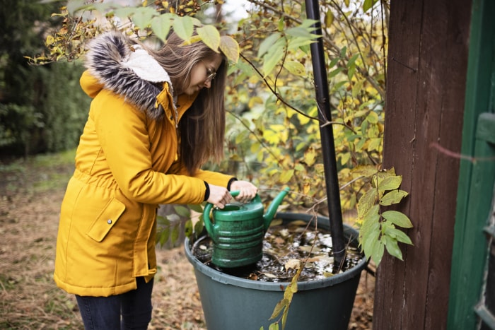 iStock-1286577244 Réserves d'eau de neige en hiver Une adolescente remplit le bidon d'eau du réservoir d'eau de pluie Photo stock.jpg