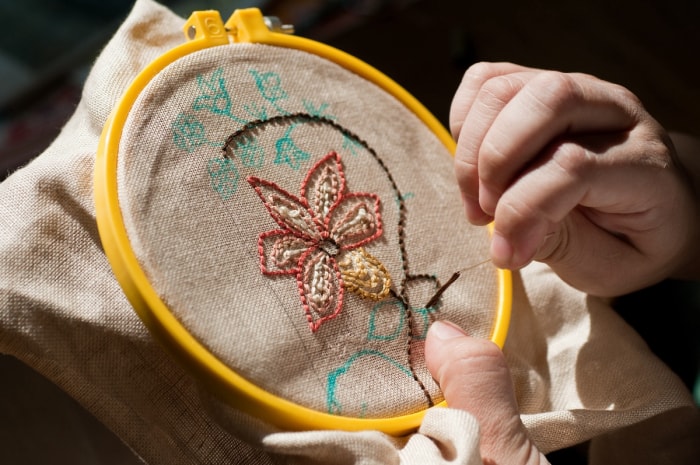 Une personne brodant une fleur sur du tissu.