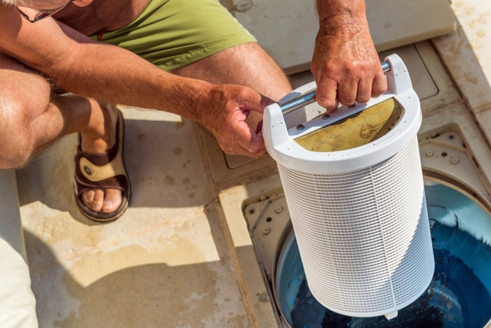 Une personne retire le système de filtration d’une piscine.