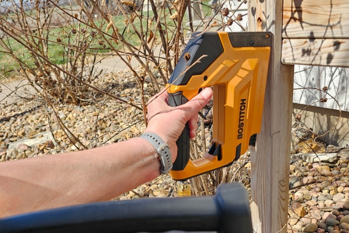 Une personne utilisant une agrafeuse à couronne Bostitch à l'extérieur pendant les tests.