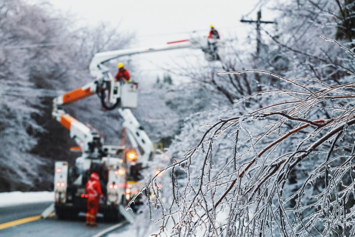 Les travailleurs d'un cueilleur de cerises rétablissent l'électricité pendant une tempête de glace hivernale.