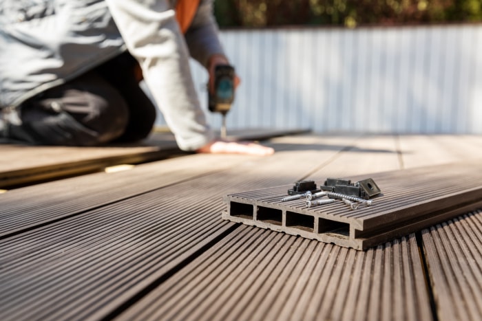 construction de terrasse en composite bois-plastique - ouvrier installant des lames de terrasse en composite bois-plastique