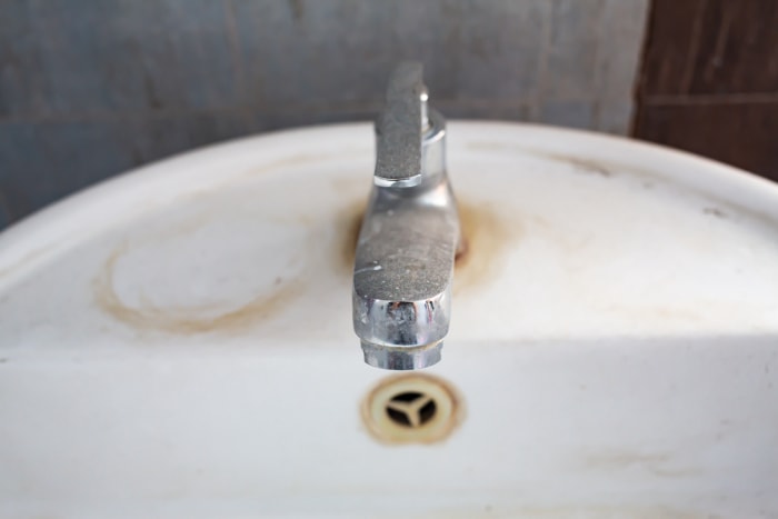 gros plan sur un vieux robinet avec des taches de rouille sur le lavabo