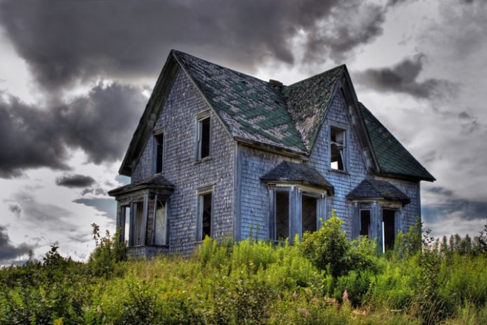 Maison hantée style vieille ferme dans un champ sous les nuages