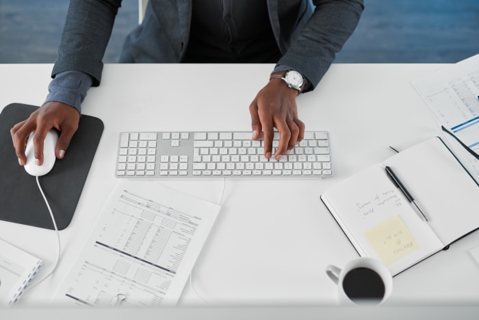 Plan recadré en plongée d'un jeune homme d'affaires utilisant un ordinateur à son bureau dans un bureau moderne