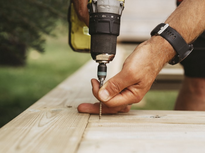 Tournevis et homme construisant une terrasse en bois à l'extérieur dans son jardin