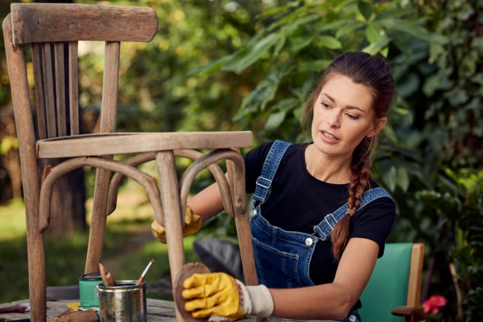 Femme travaillant sur une chaise en bois d'extérieur.