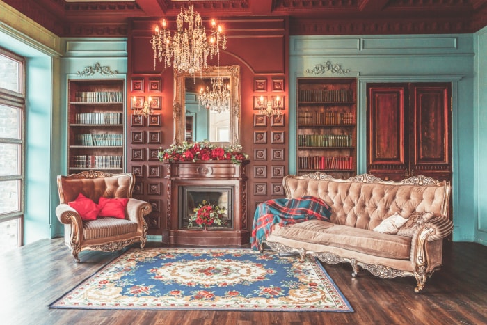 Le salon d'une maison ancienne aux murs lambrissés dispose d'une cheminée avec une composition florale.