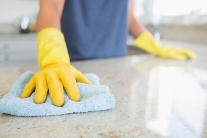 Une personne avec des gants jaunes essuie le comptoir.