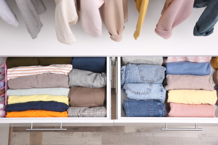 vue en plongée d'un tiroir de penderie ouvert avec des vêtements soigneusement pliés à l'intérieur et des vêtements suspendus au-dessus