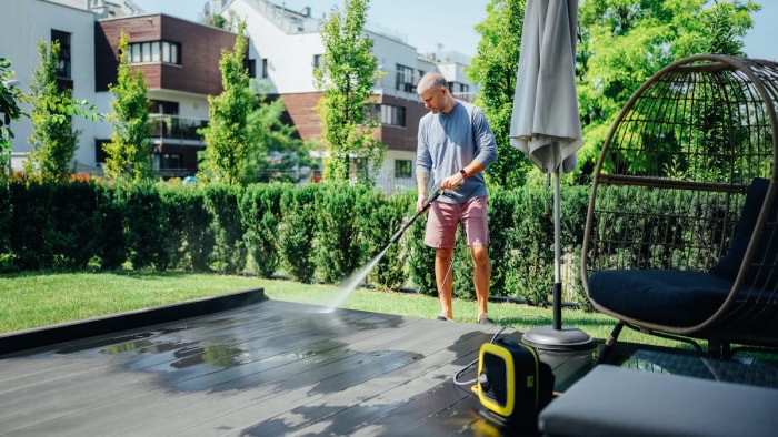 Homme mature nettoyant la terrasse avec un nettoyeur haute pression.