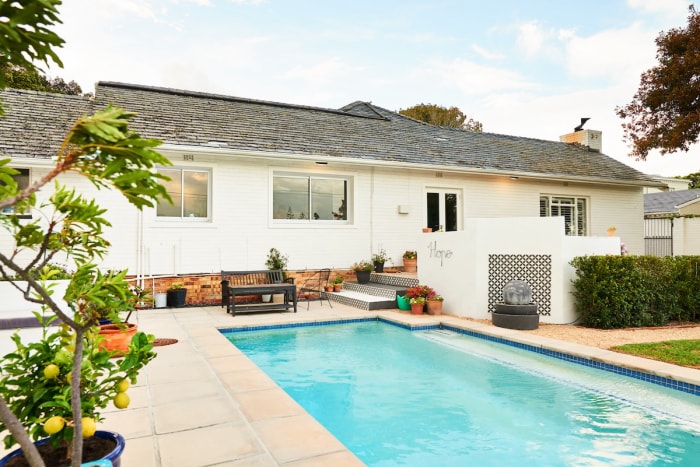 Maison de style ranch blanc avec une petite piscine dans l'arrière-cour.