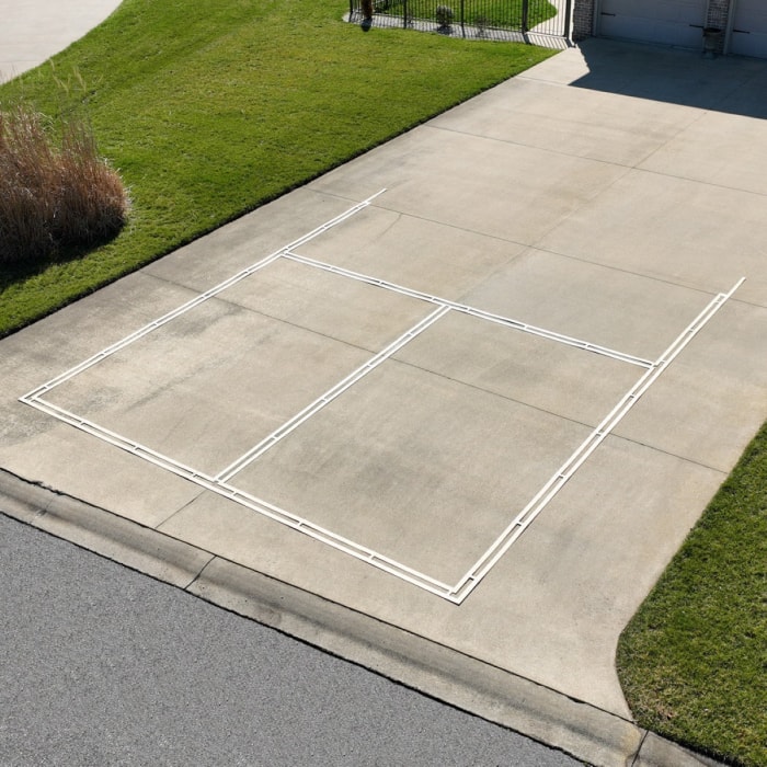 Un pochoir de terrain de pickleball est disposé sur l'allée.