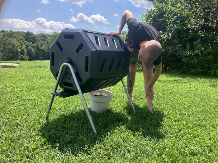 Une personne vide le compost du composteur à tambour extérieur FCMP