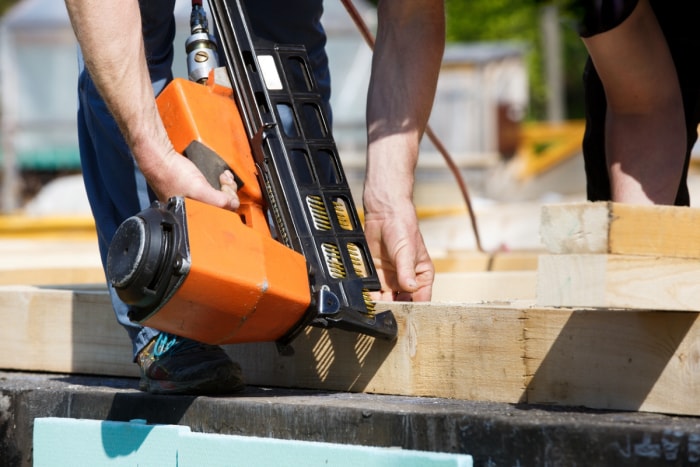 les outils électriques les plus dangereux - un homme utilisant un pistolet à clous orange