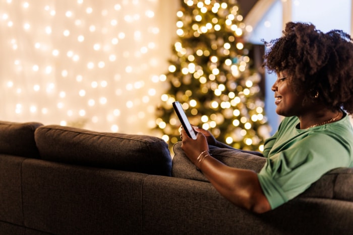 Une femme utilise son téléphone près des lumières de Noël